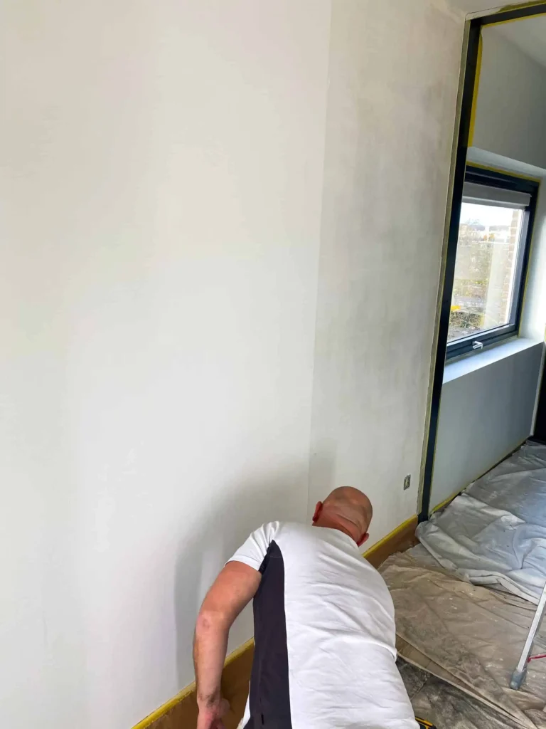 Een schilder die bezig is met het behangen van een woning met renovlies behang